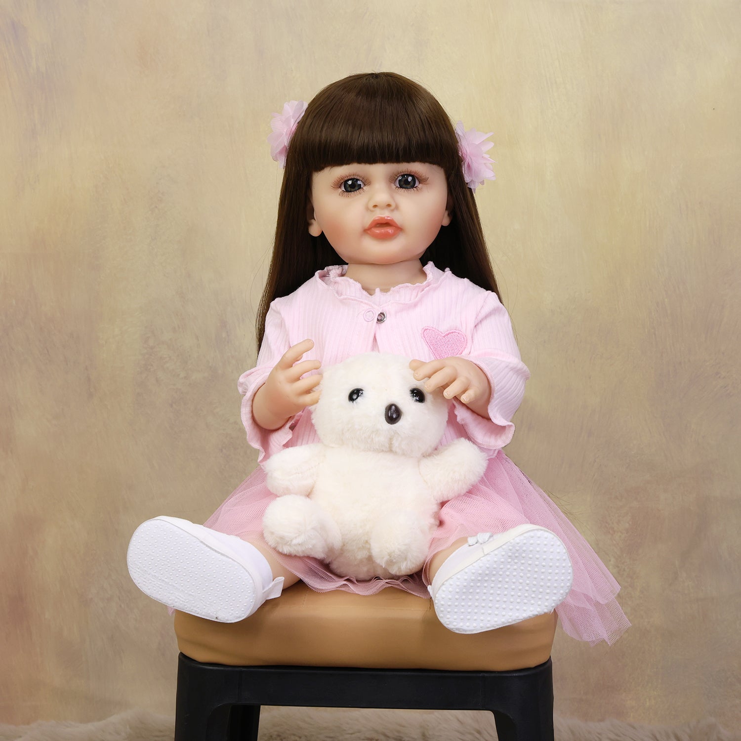 KEIUMI Lily reborn toddler doll in a pink outfit sitting.