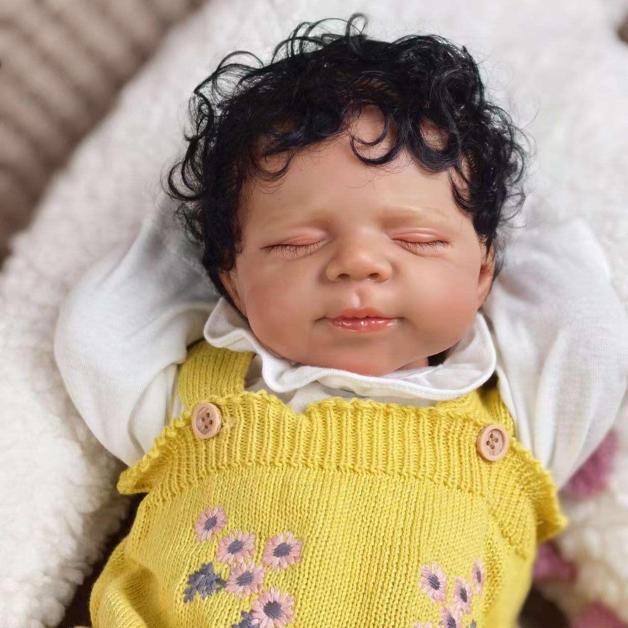 Close-up of the reborn doll's serene sleeping face and dark curly hair.