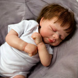 Realistic reborn baby doll's tiny hand resting on its chest.