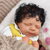 Reborn doll with medium-dark skin, wearing a yellow romper and pink pacifier.