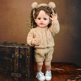 KEIUMI Clover toddler reborn doll sitting, showing full knitted outfit.