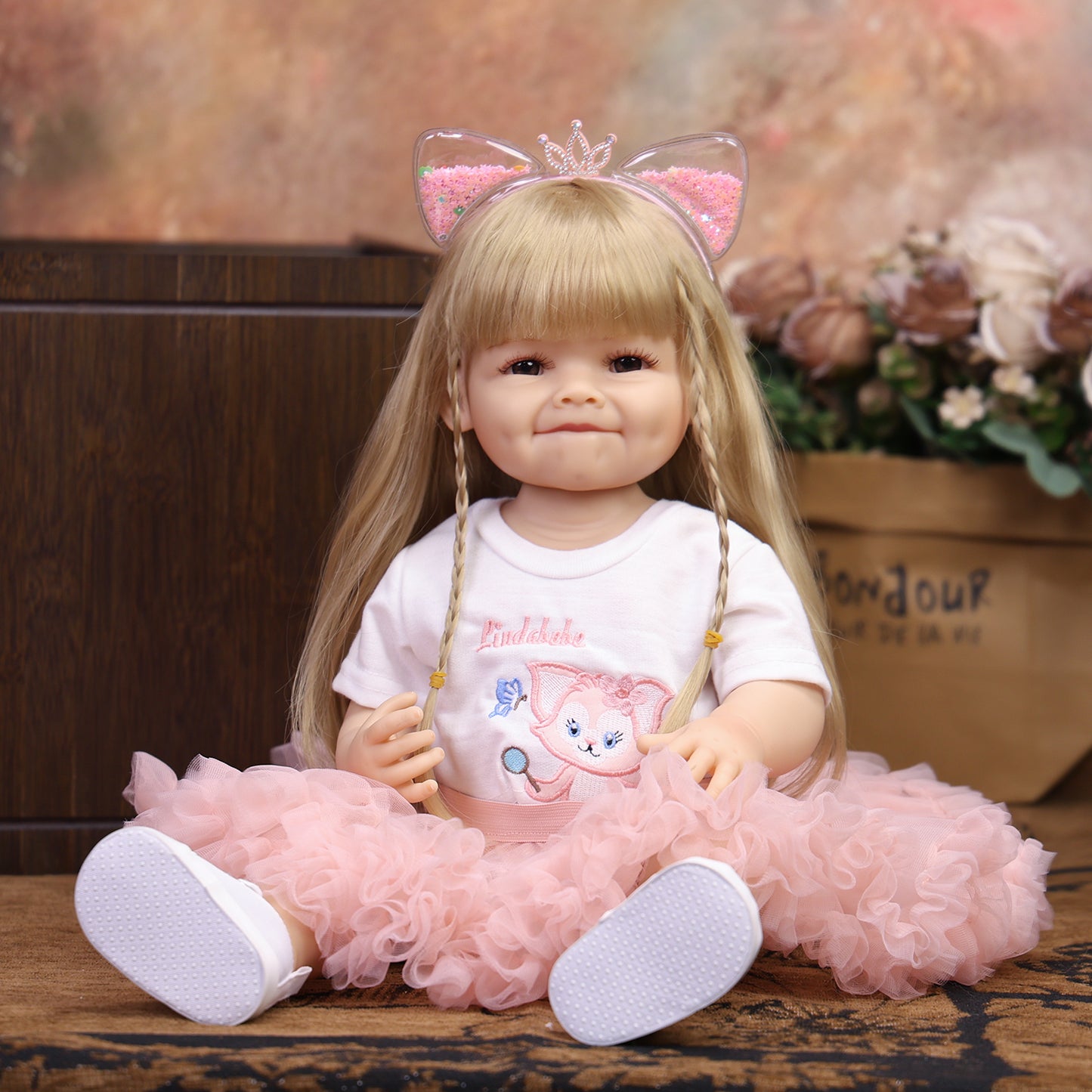 KEIUMI blonde reborn toddler doll smiling, wearing pink cat outfit and headband.