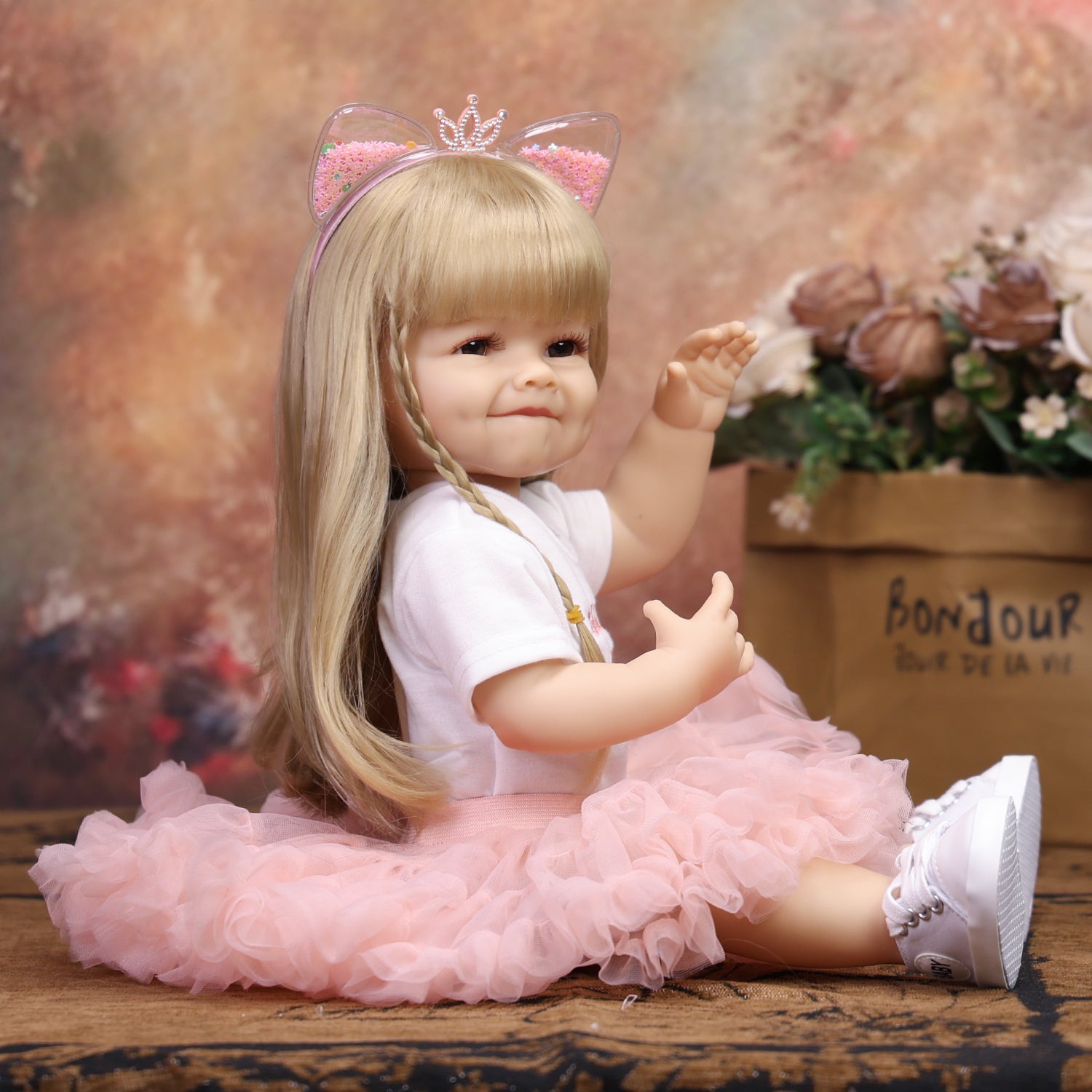 Full body view of blonde reborn doll in pink tutu skirt and white sneakers.