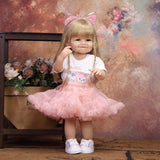 Reborn doll sitting, showing white t-shirt with 'Lindababe' and pink cat graphic.