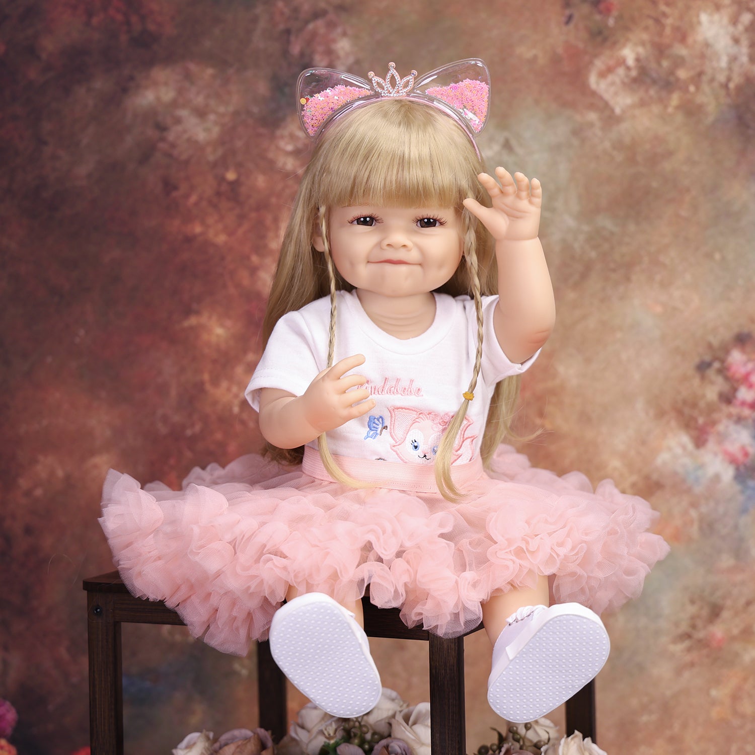 Side profile of smiling blonde reborn doll wearing glitter cat ear headband.