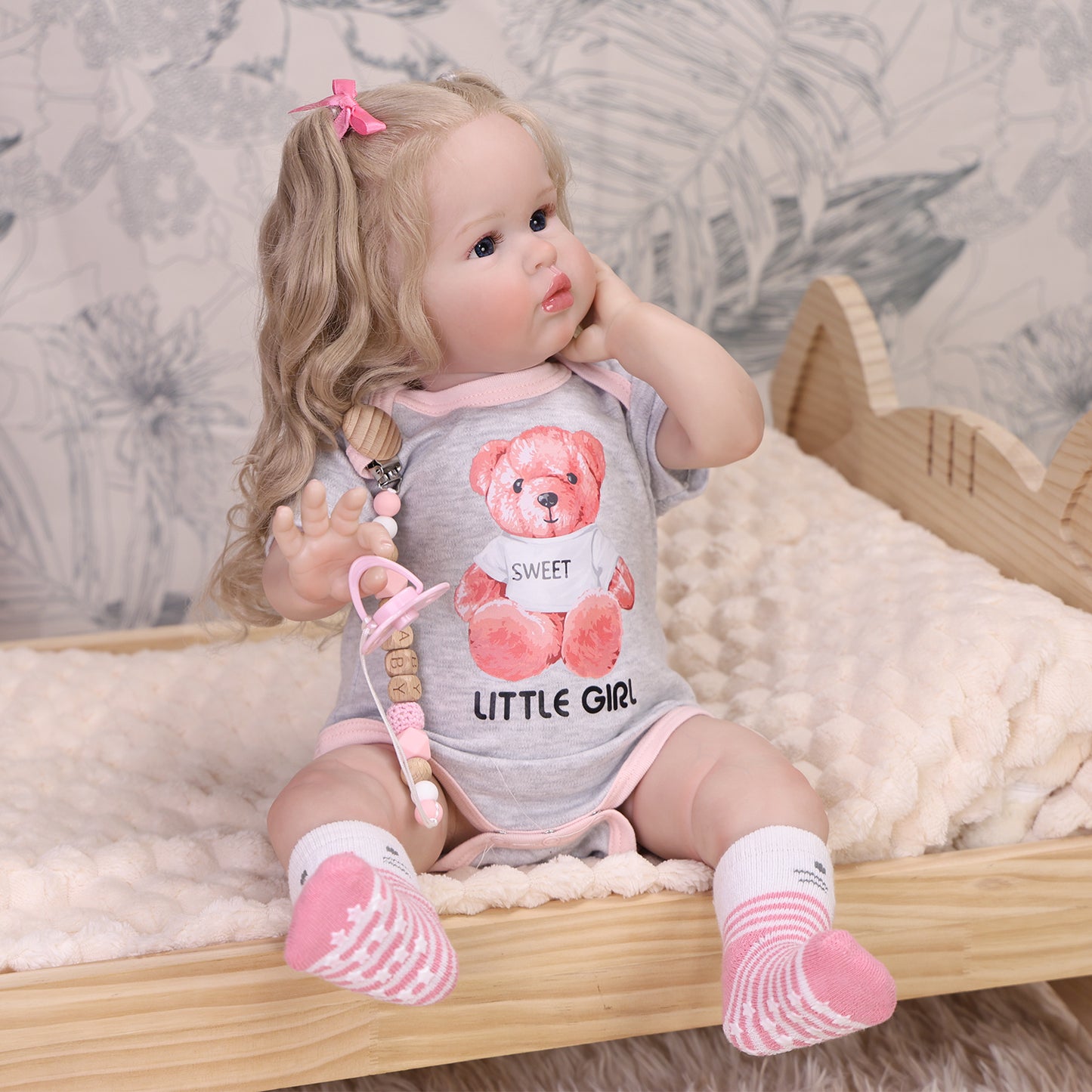 Penny reborn doll lying down, showcasing her full body and playful outfit.