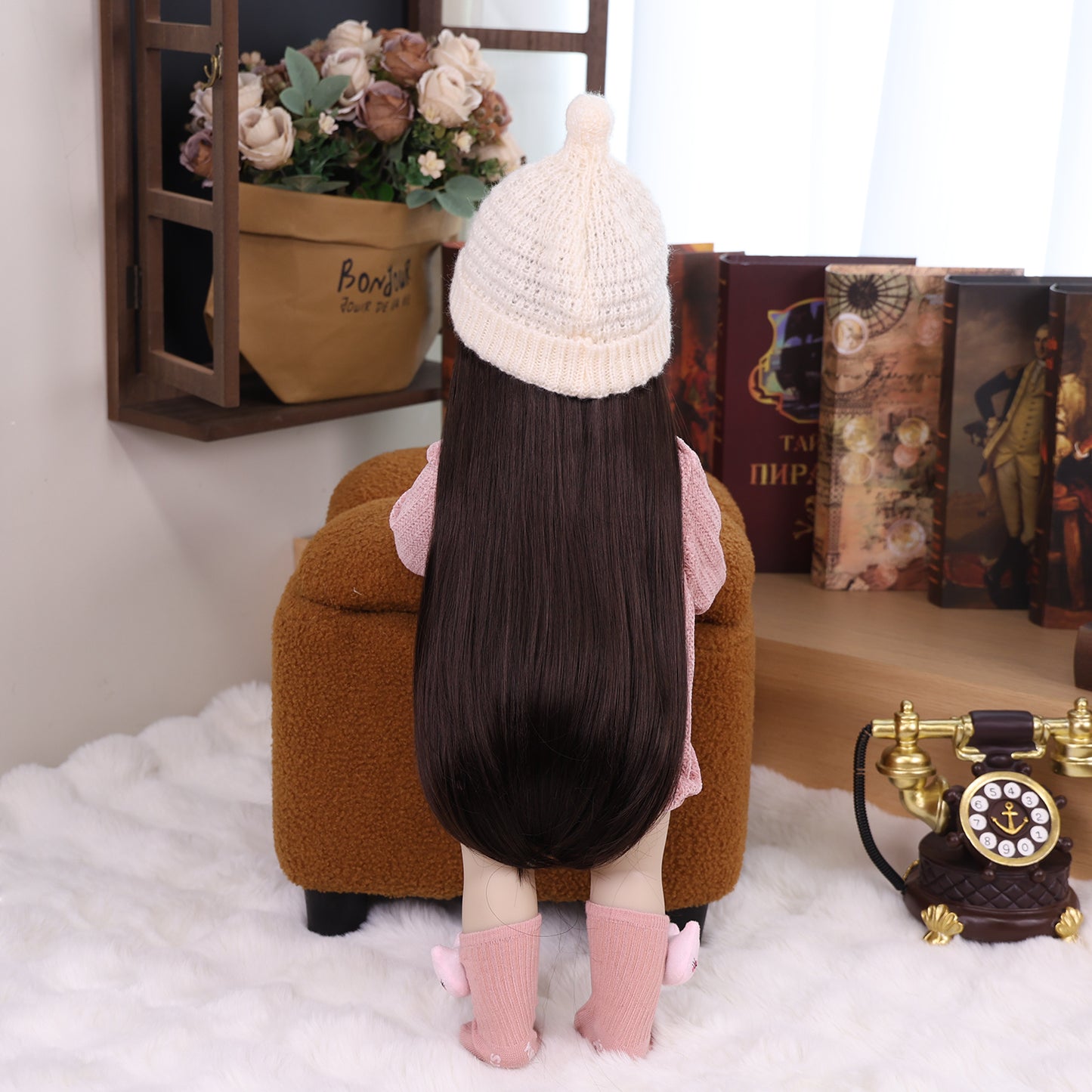 KEIUMI Elara reborn toddler doll with long dark hair, wearing pink knitted romper.
