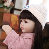 KEIUMI Elara doll sitting, showing her pink knitted romper and cream beanie.