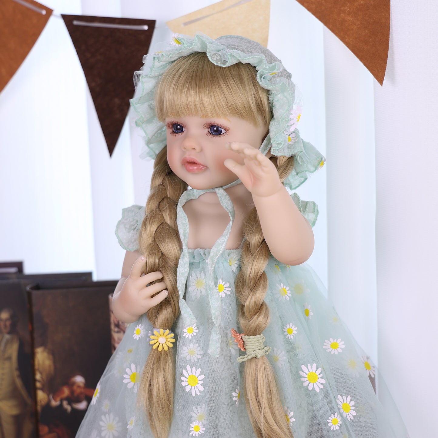Lifelike silicone reborn doll wearing a mint green daisy outfit and bonnet.