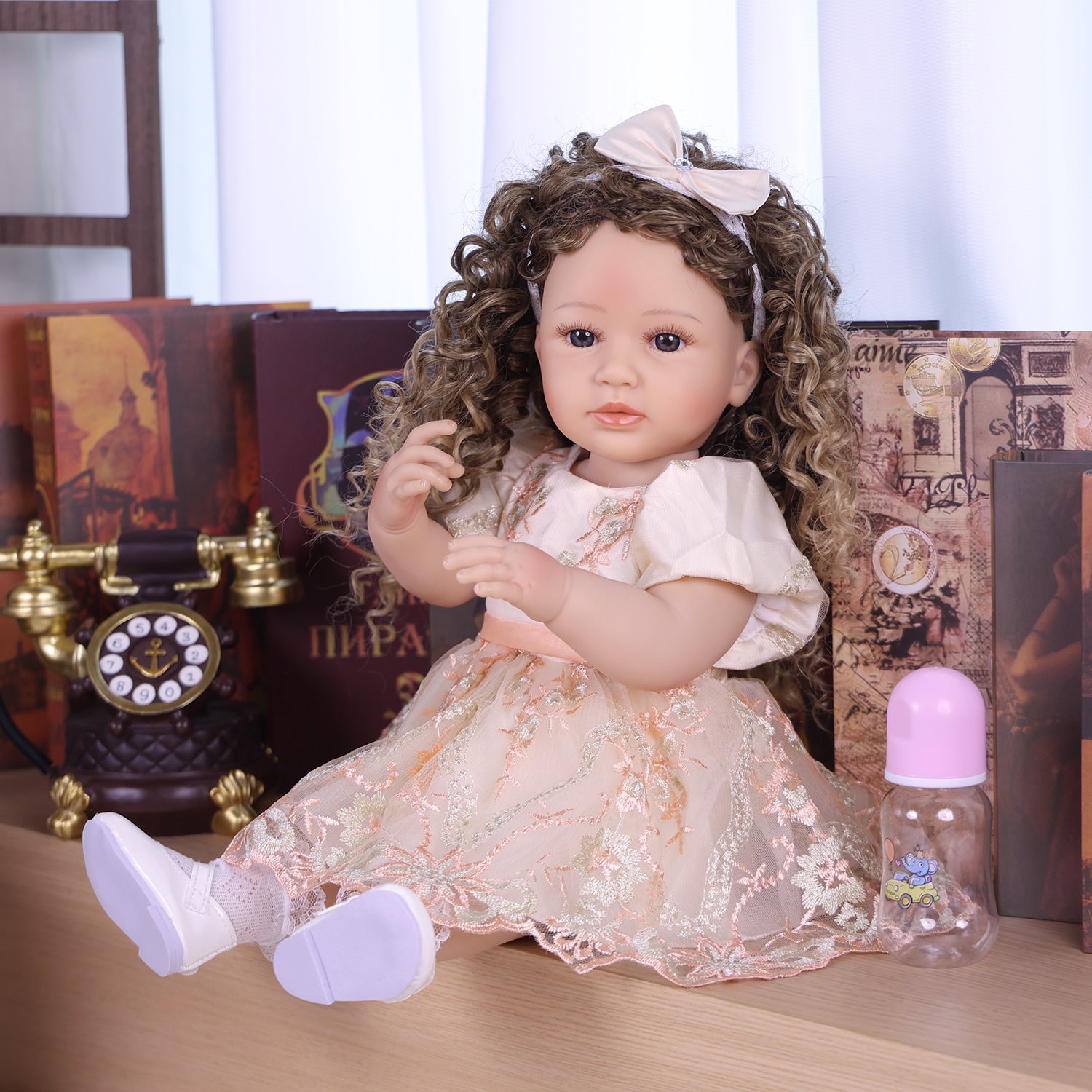 Full view of Emmeline reborn doll standing, showcasing her embroidered gown and shoes.