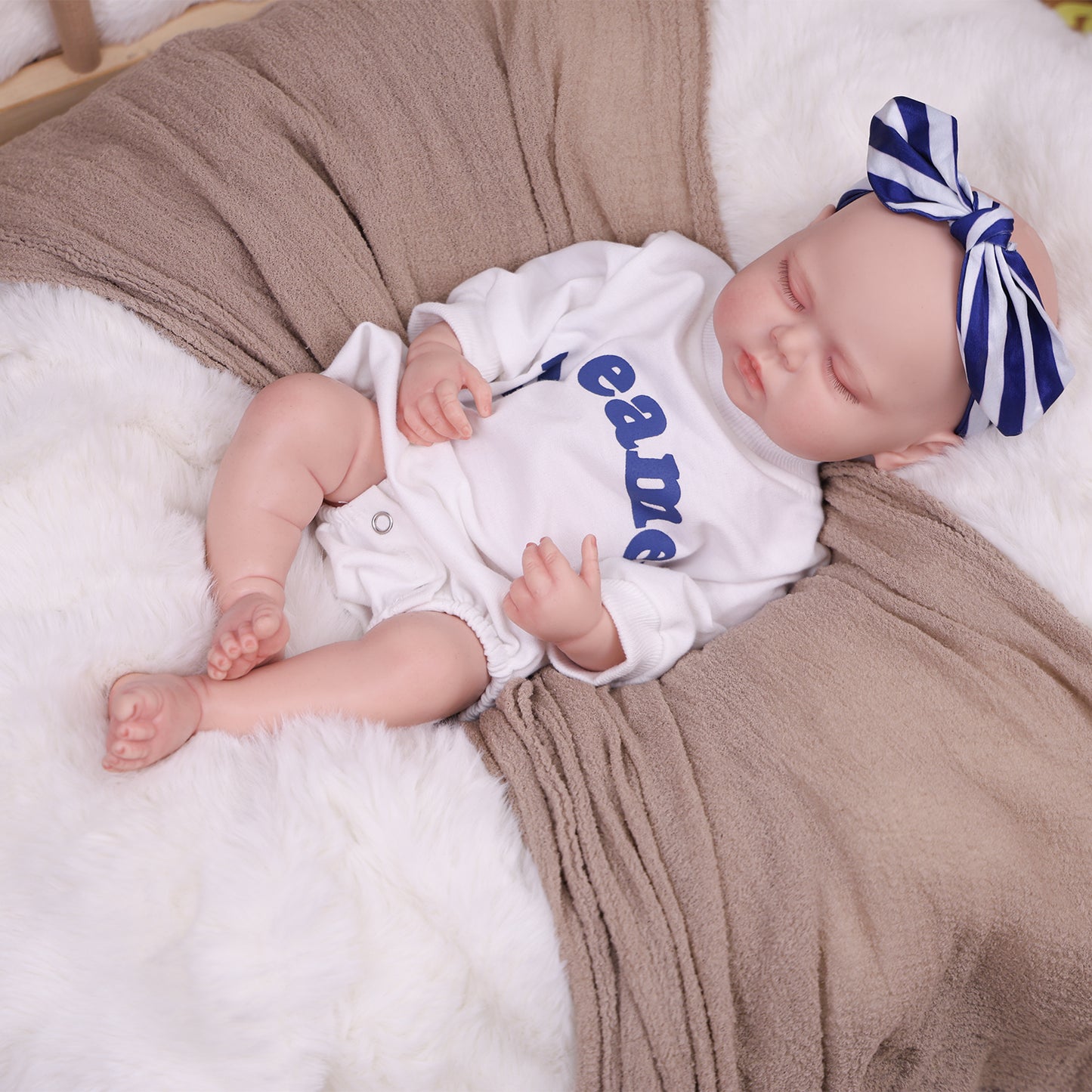 KEIUMI Dreamer reborn doll sleeping peacefully in a white romper with 'dreamer' text.