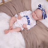KEIUMI Dreamer reborn doll sleeping peacefully in a white romper with 'dreamer' text.