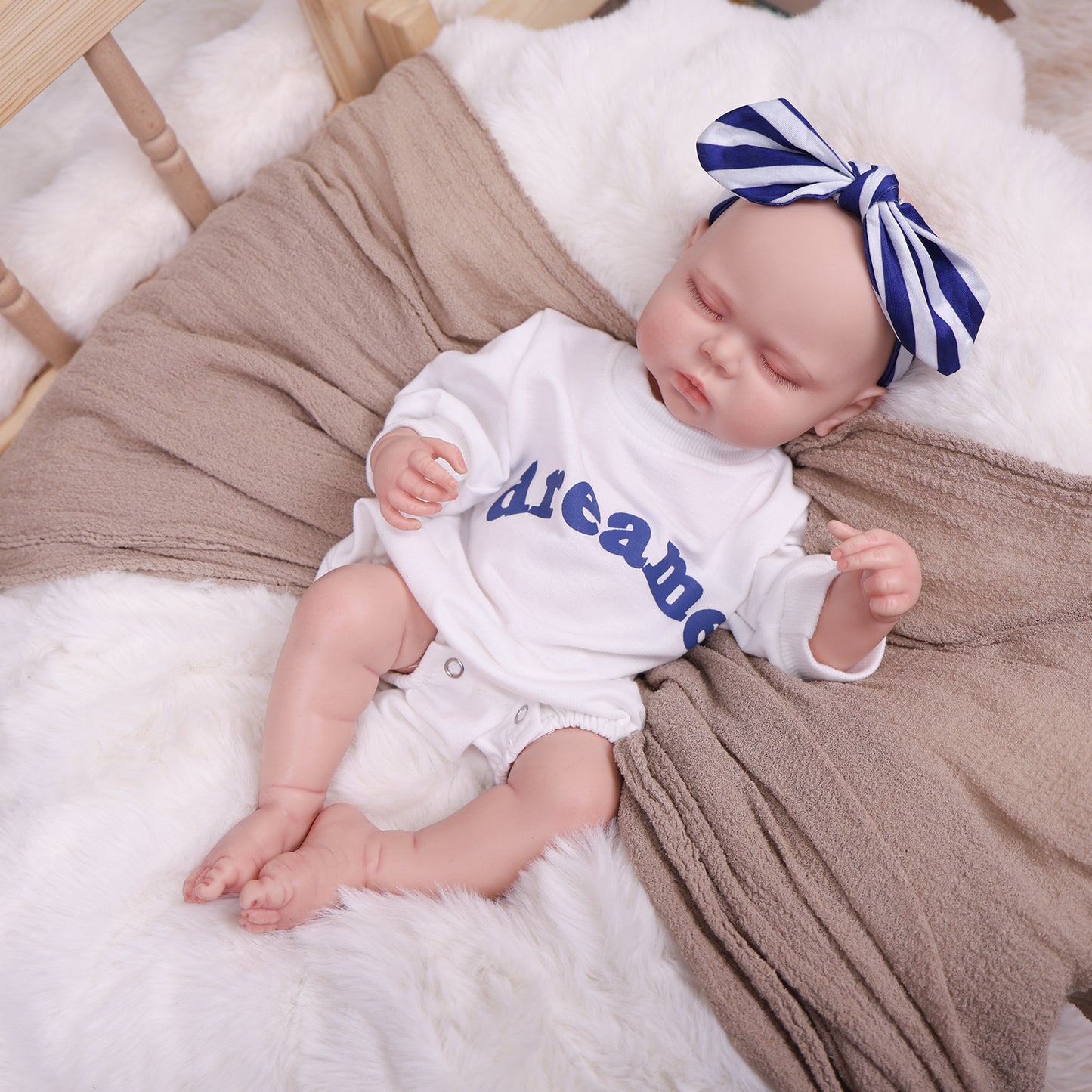 Full body shot of the sleeping reborn doll, dressed in its 'dreamer' outfit.