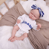Full body shot of the sleeping reborn doll, dressed in its 'dreamer' outfit.