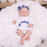 The reborn doll's back, showing the simple design of the white romper.
