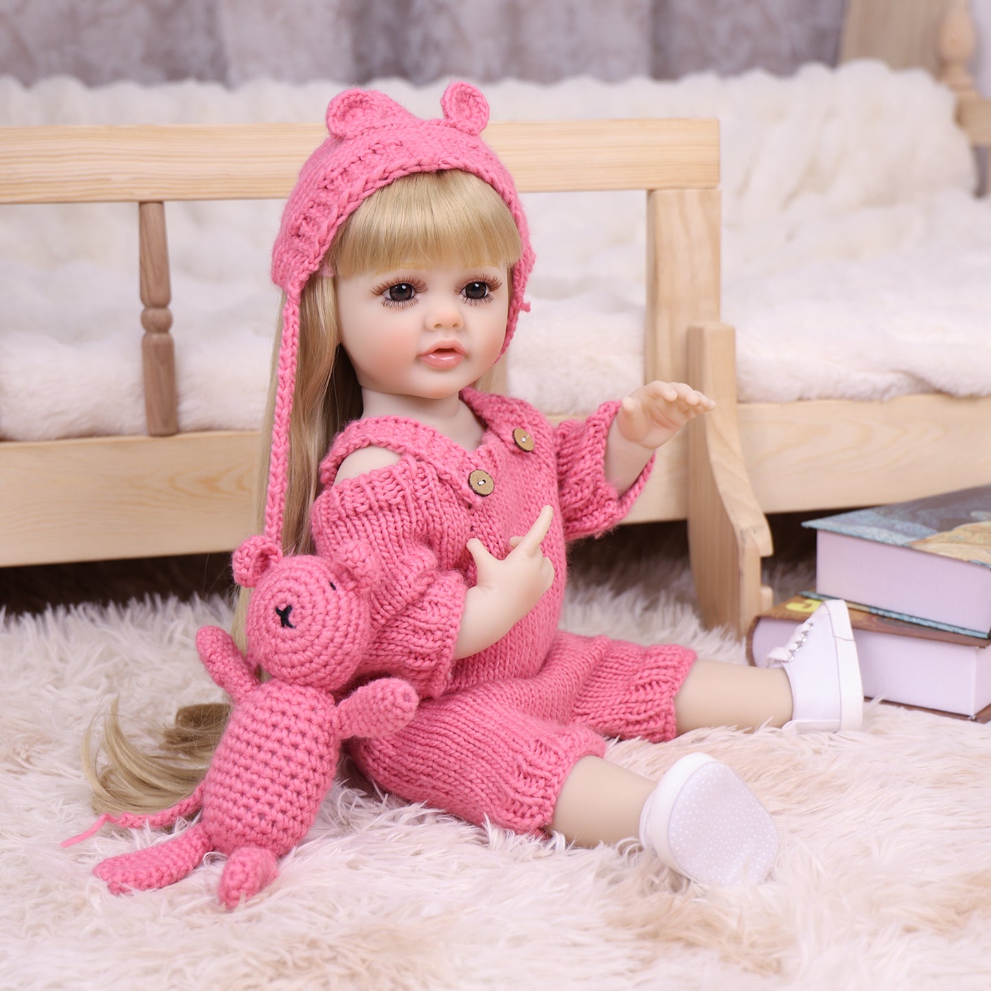 Maisie reborn doll with pink knitted bear toy, pacifier, and baby bottle.
