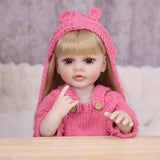 Side view of Maisie reborn doll showing blonde hair and pink knitted hat.