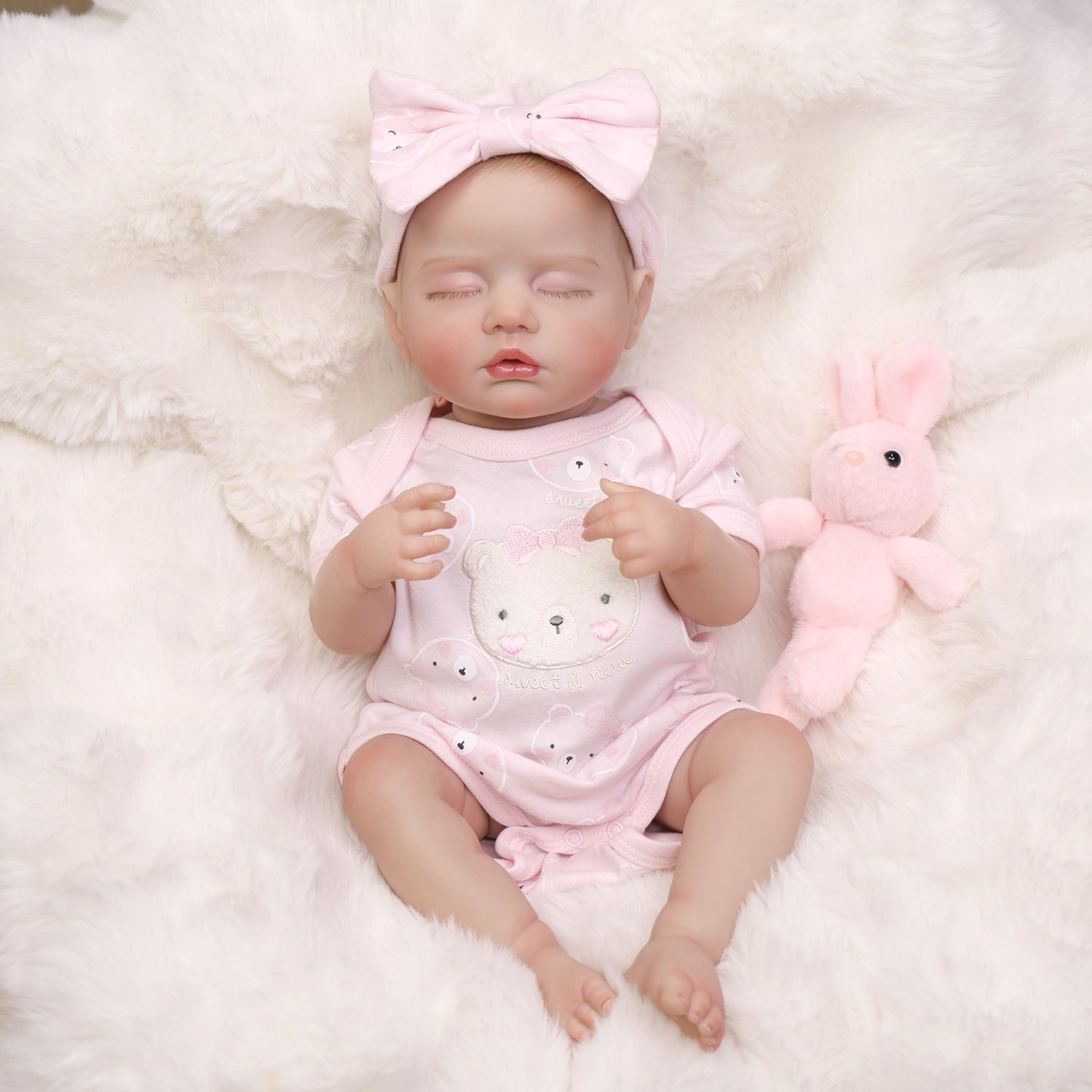 Full view of KEIUMI Dreaming Blossom reborn doll sleeping in pink romper.