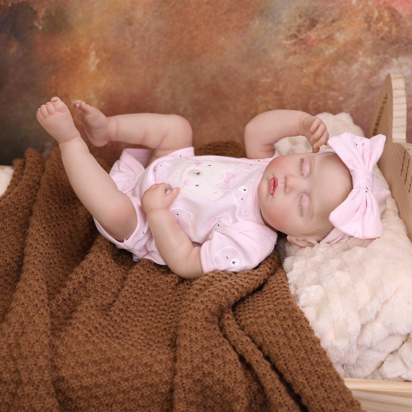 Lifelike reborn baby doll with toy, showing her delicate hands.