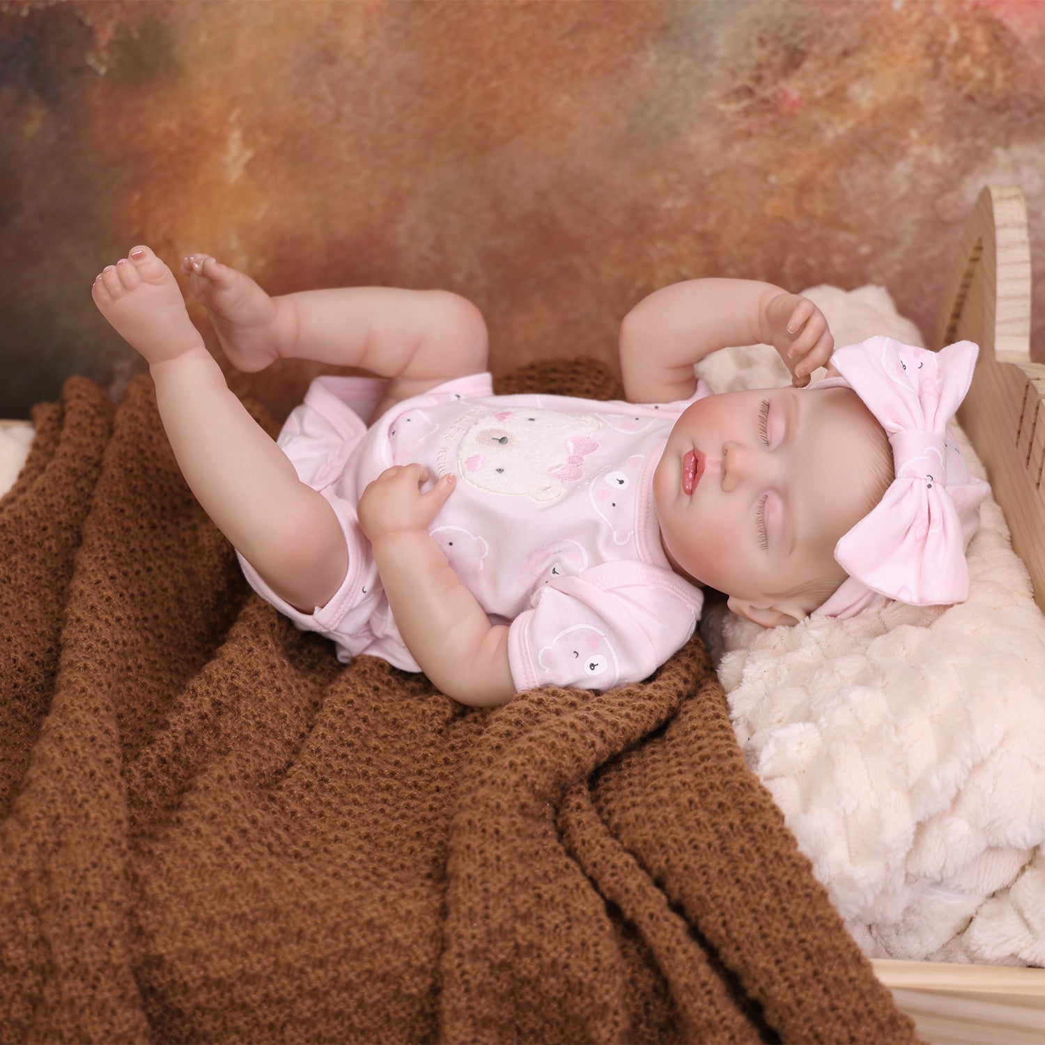Lifelike reborn baby doll with toy, showing her delicate hands.