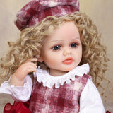 Adorable Curious Belle reborn doll seated, displaying her vibrant red tiered skirt.