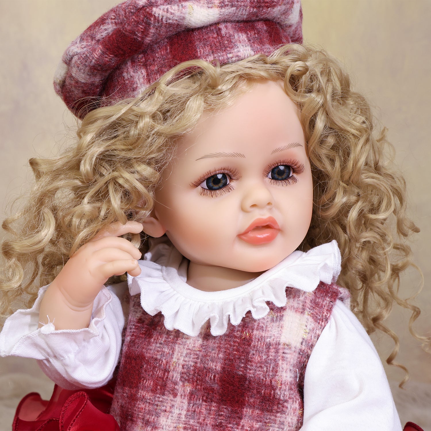 Adorable Curious Belle reborn doll seated, displaying her vibrant red tiered skirt.