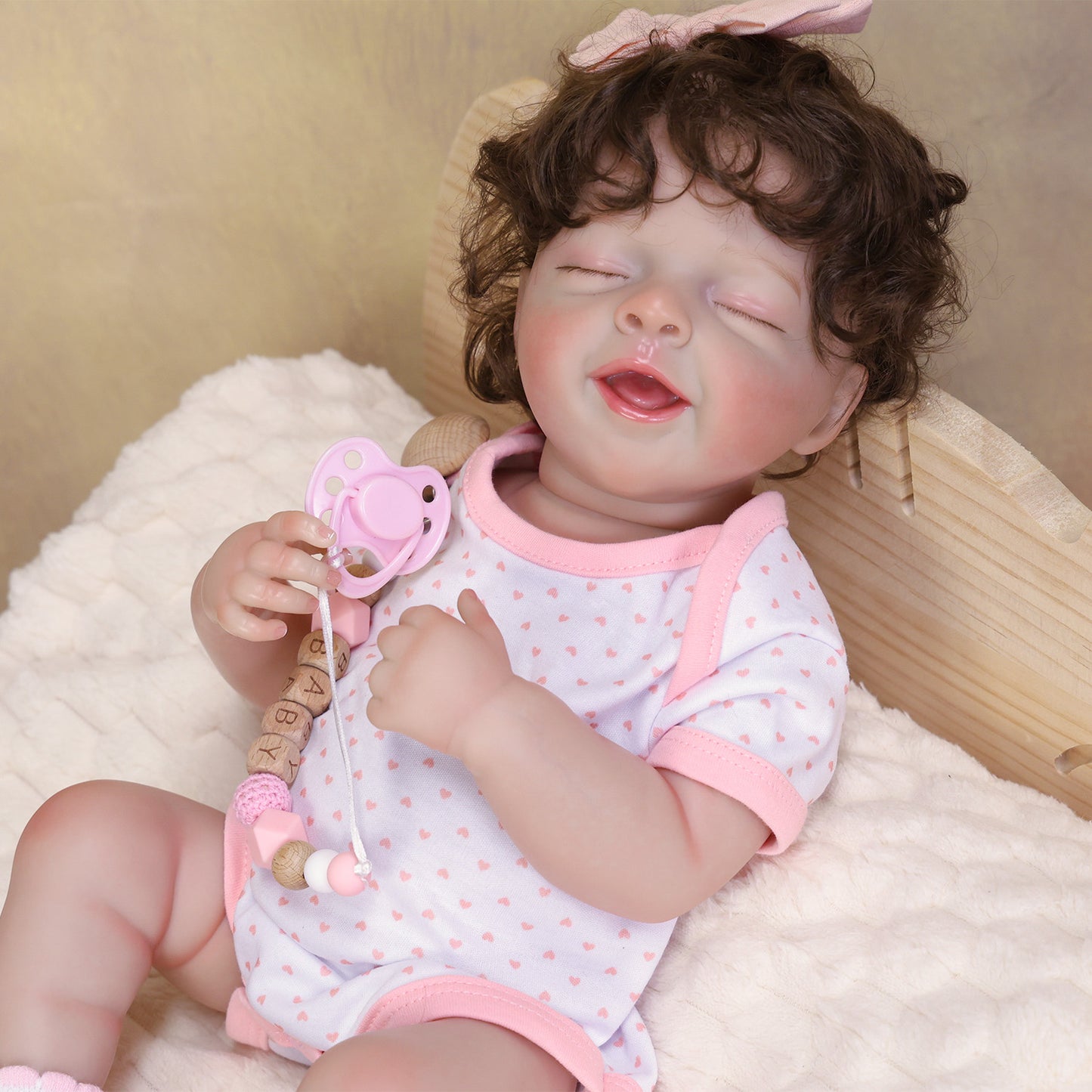 Rosalie reborn doll in a white heart-printed onesie, white socks, pink bow headband.