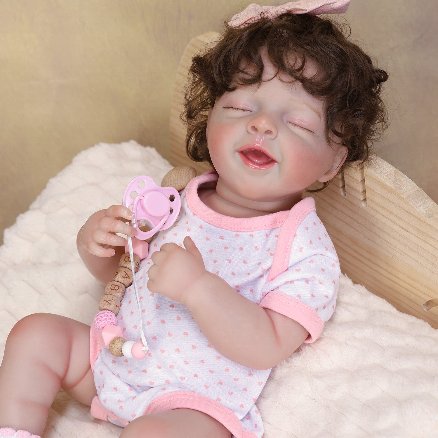 Rosalie reborn doll in a white heart-printed onesie, white socks, pink bow headband.