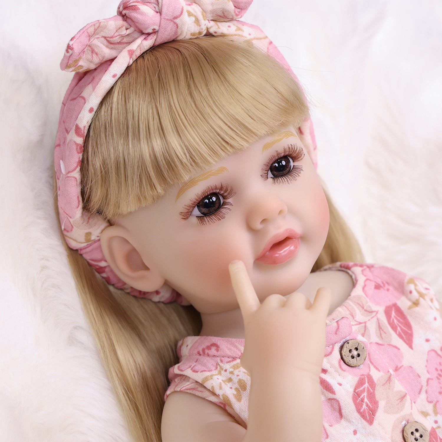 Close-up of Posy reborn doll's sweet pouting face and dark eyes.