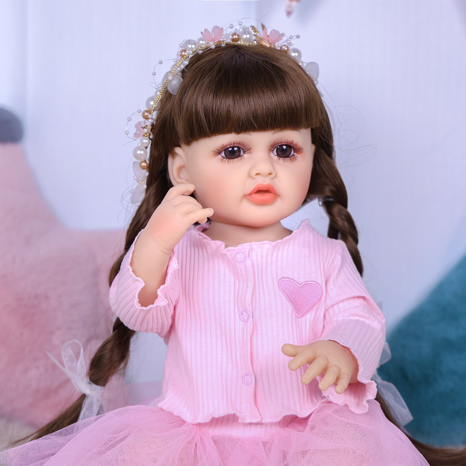 Full body shot of Lily reborn doll in pink tulle skirt and white sneakers.