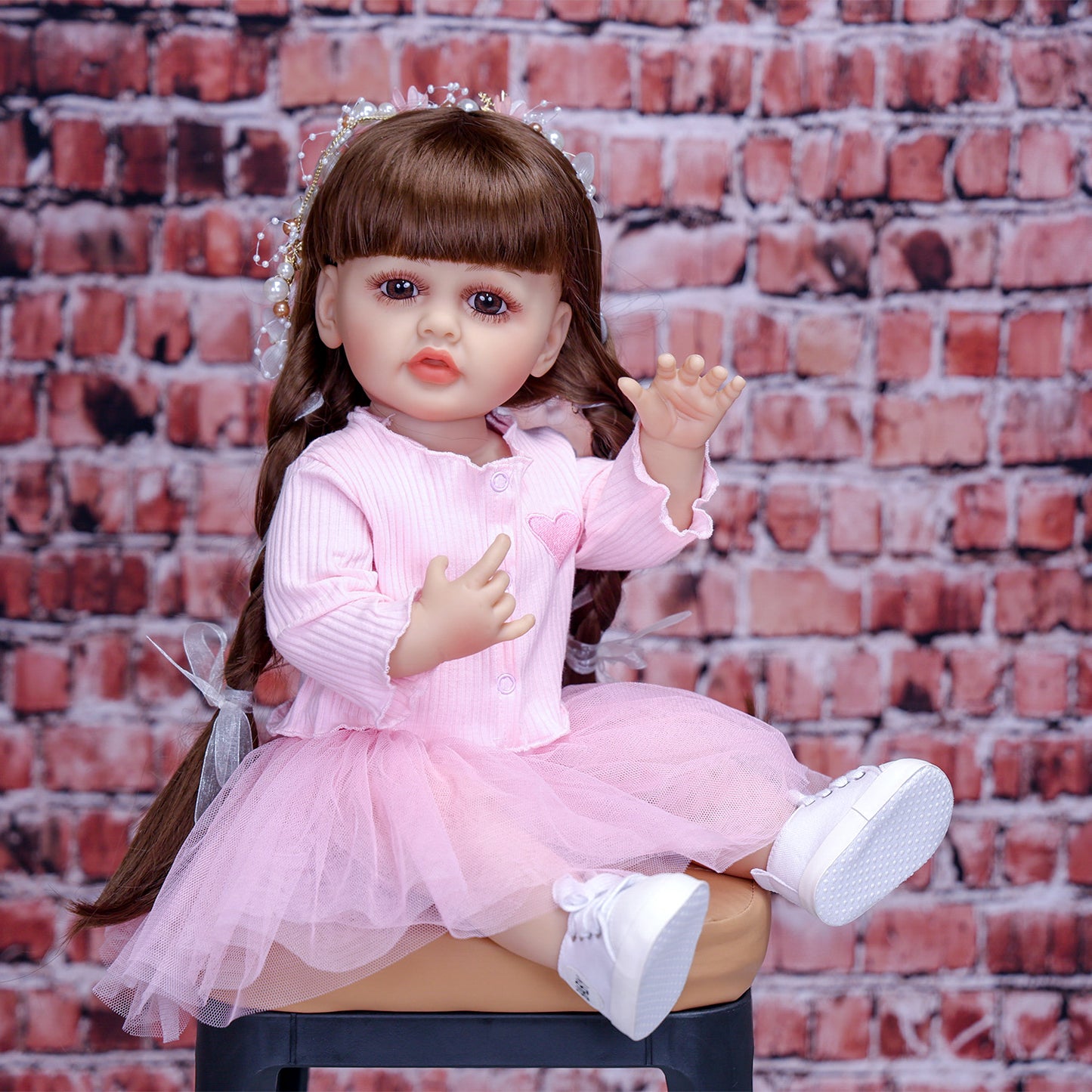 Lily reborn doll sitting with her white plush teddy bear, looking playful.