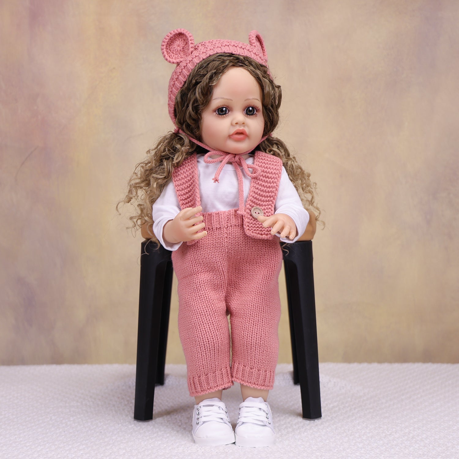 KEIUMI Sweetpea doll with pacifier, wearing pink knitted overalls.