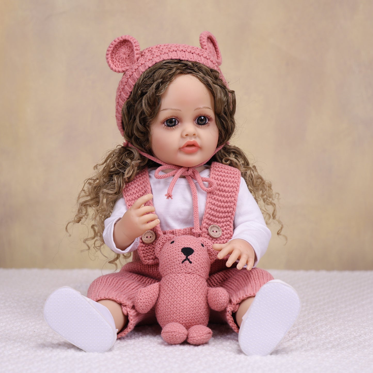Side profile of realistic reborn doll, showcasing curly light brown hair.