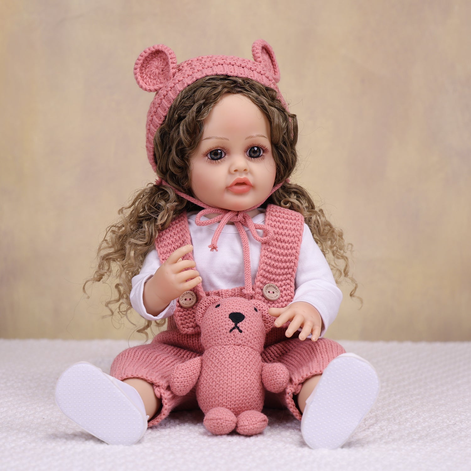 Side profile of realistic reborn doll, showcasing curly light brown hair.