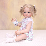 Pippa reborn doll's full body view, showcasing floral romper and accessories.