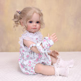 Side profile of Pippa reborn doll, highlighting her blonde pigtails and outfit.