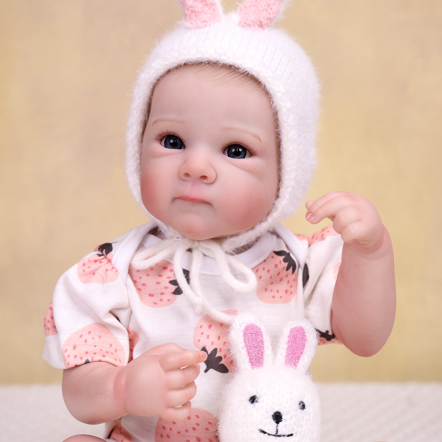 Adorable reborn doll sitting, showcasing full strawberry outfit.