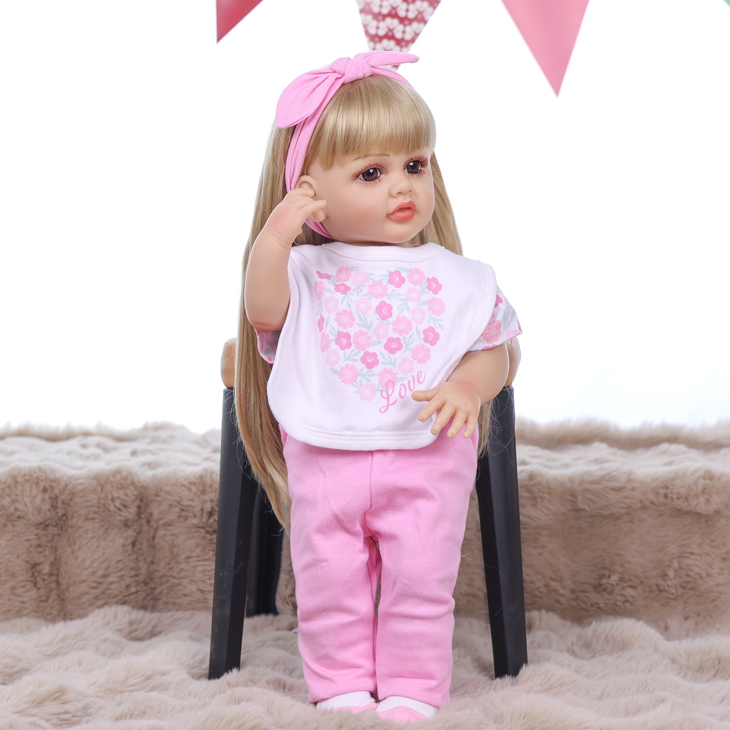 Joy reborn doll holding baby bottle, wearing pink floral bodysuit.