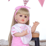 Joy doll lying down, showcasing her pink floral outfit and accessories.