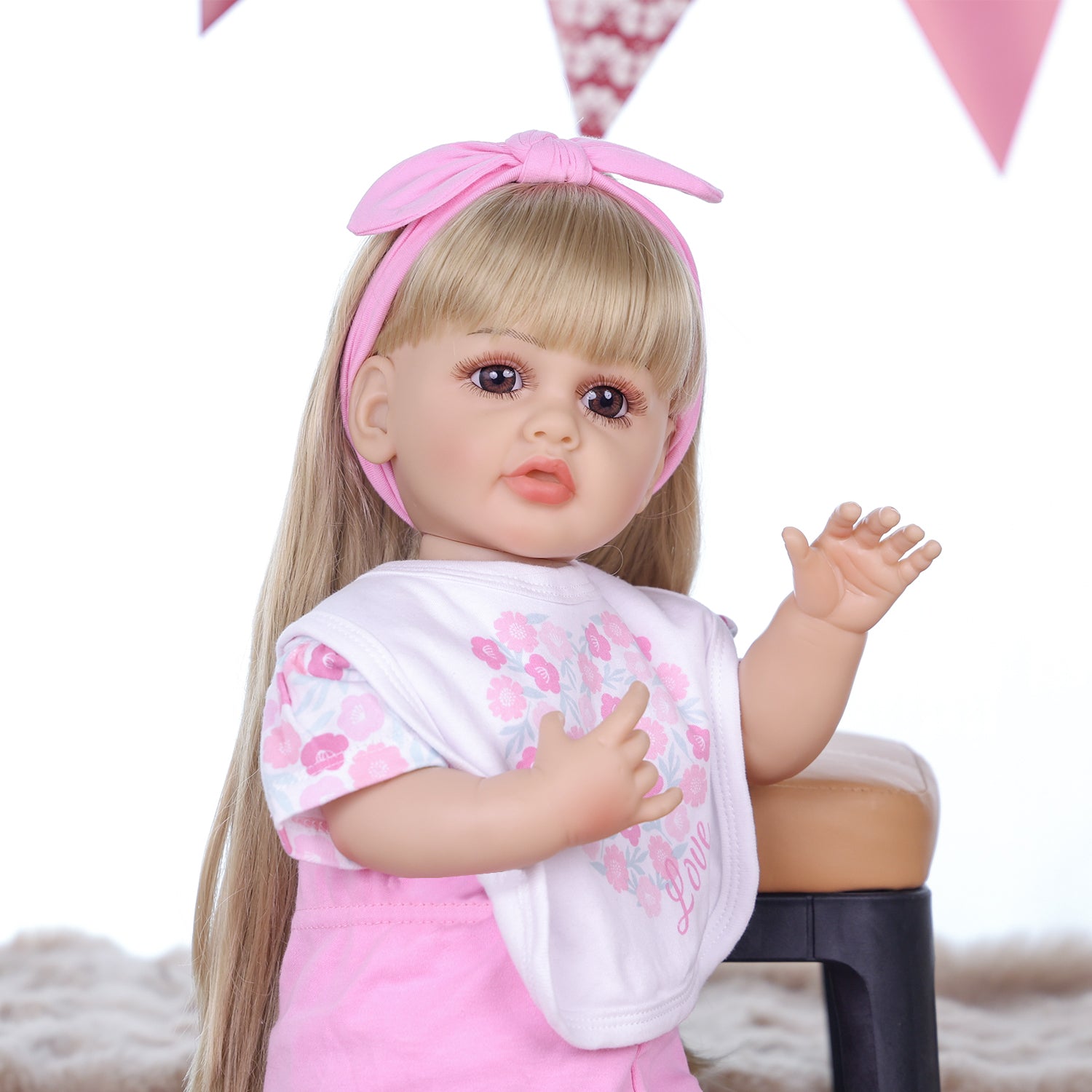 Joy doll lying down, showcasing her pink floral outfit and accessories.