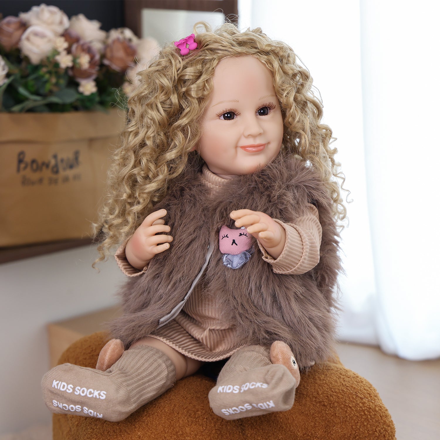 KEIUMI Sunny reborn toddler doll smiling with golden curls in full outfit.