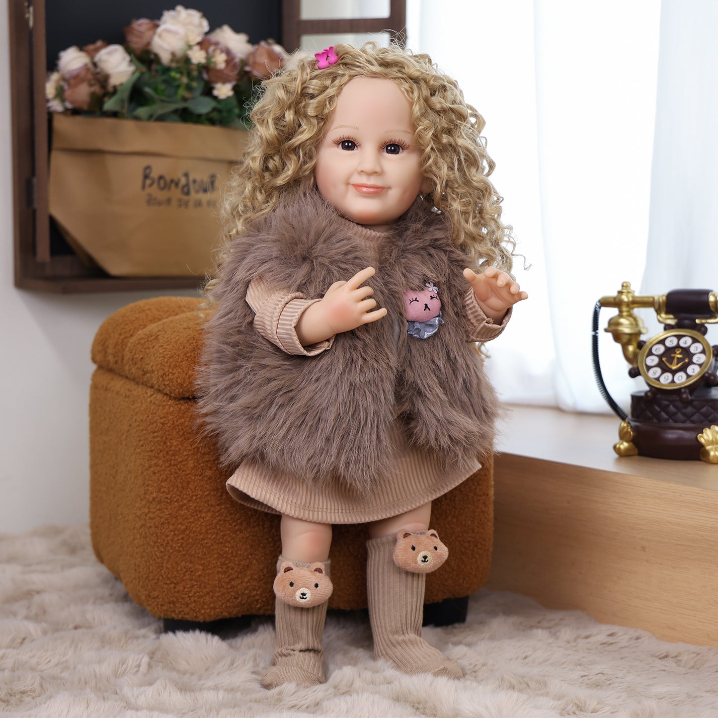 Sunny reborn toddler doll sitting, showcasing her ribbed beige dress and vest.