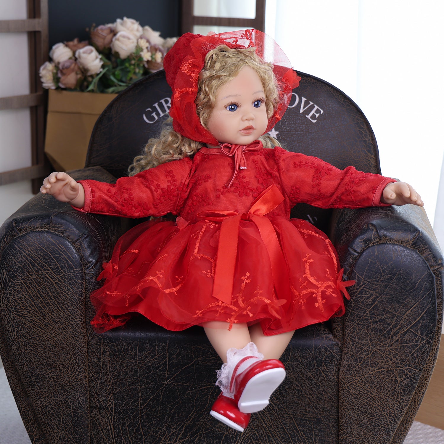 Ruby Belle toddler doll in full red ensemble, sitting with a white teddy bear.